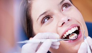 woman getting checkup by dental assistant