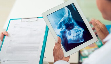 dentist holding tablet with x-rays on it
